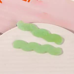 Macro shot of wavy light green acetate hair clips with marble texture on white plate