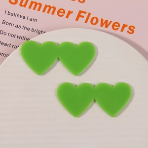 Detail shot of fruit green acrylic double heart charms on a white textured plate