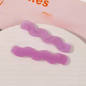 Detail of purple wavy acetate hair clips with marble texture on a ceramic plate