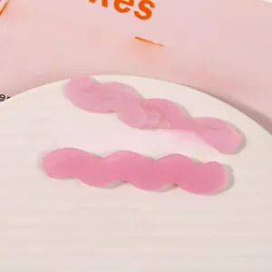 Detail of pink wavy resin hair clips with marble texture and matte finish on a tray