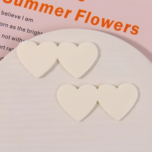 Close-up of cream white double heart acrylic charms for DIY hair accessories on white plate