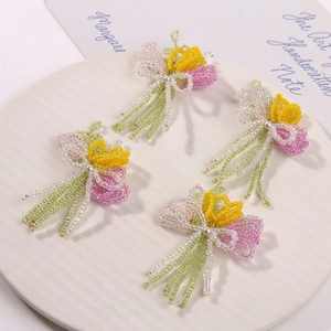 Handmade beaded tulip flower hair clip accessories in pink and yellow on a ceramic tray