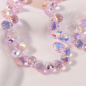 Macro shot of faceted pink AB Aurora glass teardrop beads on white ceramic background