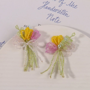 Handmade beaded tulip flower earrings with colorful beads and pearl accents on a plate