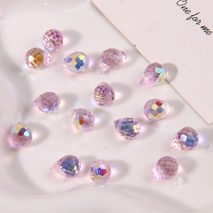 Detailed macro view of faceted Aurora AB pink glass teardrop beads on white tray