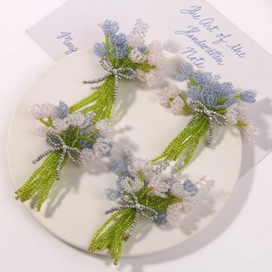 Macro shot of handmade beaded flower charms with a silver bow detail on a white tray