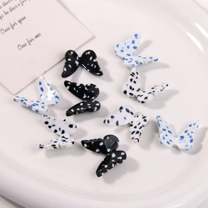 Polka dot acetic acid butterfly charms in black and white on a ceramic plate for DIY crafts