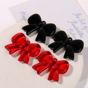 Macro detail of red translucent and black glossy resin bow pendants for DIY jewelry