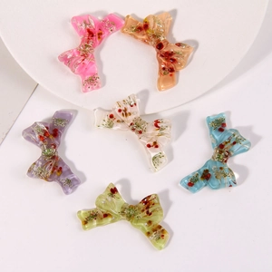 Detail showing translucent resin bow hair clips with embedded natural dried flowers