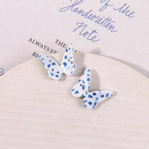 Detail view of butterfly acetate earrings with blue polka dot pattern on cream base