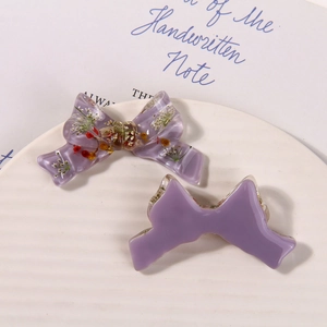 Detail of purple resin bows with embedded dried flowers on a white ceramic plate