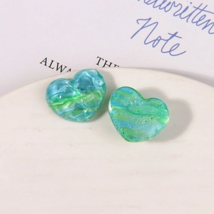 Macro view of heart-shaped resin charms with green marble texture and pearlescent finish
