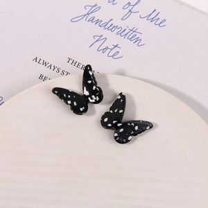Detailed view of handmade black resin butterfly charms with white polka dot patterns