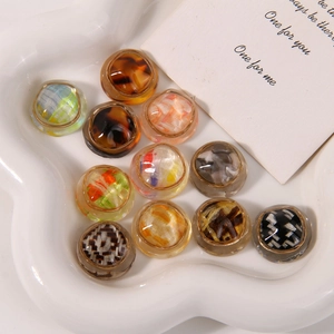 Detailed close-up of colorful resin buttons with woven texture and gold edges on a ceramic plate