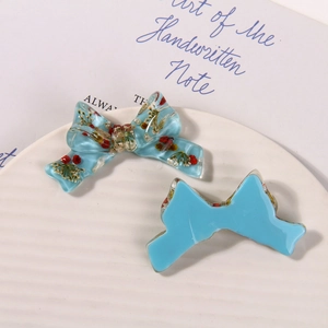 Detailed view of handmade light blue resin bow charms with embedded dried flowers