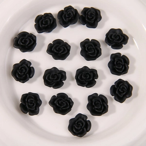 Detalle de 15 piezas de flores de rosa de resina negra mate en un plato de cerámica blanca