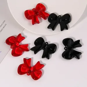 Detail of red and black bow charms for jewelry making on a white surface