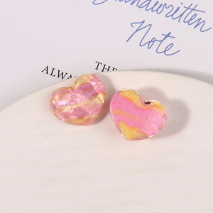 Close-up of pink and gold marble resin heart charms with glitter on a white plate