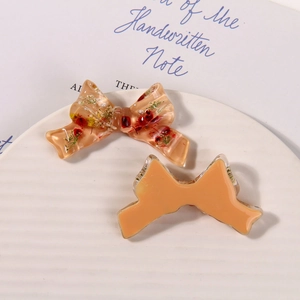 Detail of resin bow accessories with dried flowers on a white textured display plate