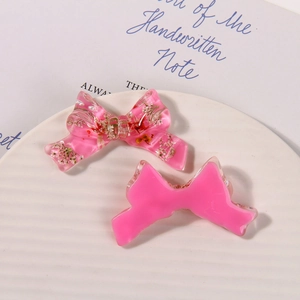 Detail of pink resin bow with dried flowers for DIY hair accessories on white plate