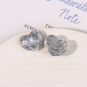Macro detail of heart-shaped resin charms with grey marble texture and silver glitter
