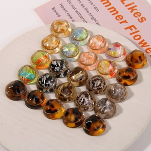 Flat lay of vintage tortoise resin round buttons with gold metal bases on a white tray
