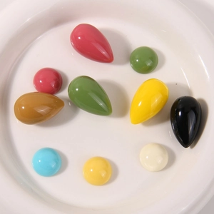Macro van kleurrijke harsdruppelkralen voor DIY-sieraden op een wit keramiek bord