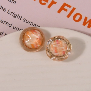 Close-up of circular resin earrings with woven texture and gold metal border detail