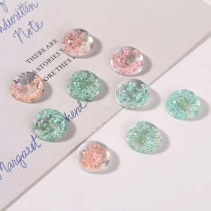 Macro shot of clear resin cabochons with pink and blue dried flowers for DIY jewelry making