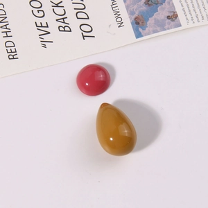 Detail van gepolijste rode ronde en gele druppelvormige harskralen voor DIY-sieraden