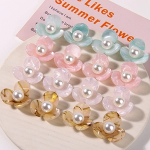 Macro detail of colorful acetate flower hair accessories with pearls in a ceramic dish