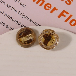 Close-up of asymmetric resin earrings with woven straw fiber inlay on ceramic dish