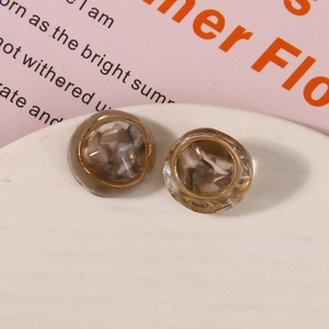 Macro shot of retro amber resin stud earrings with gold woven edge on a white tray