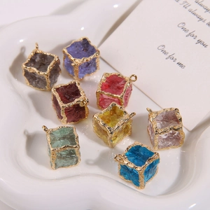 Close-up of eight colorful resin cube charms with irregular gold metal edges in a heart dish