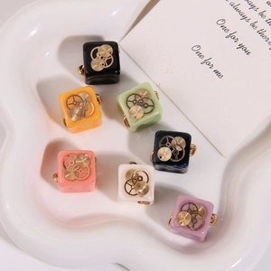 Macro shot of assorted colorful resin cube charms with gold gear accents in a heart dish