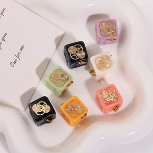 Macro view of colorful resin square charms with steampunk gears and gold hanging loops
