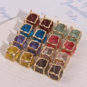 Detail of colorful resin cube pendants with gold metal edges arranged on a white tray