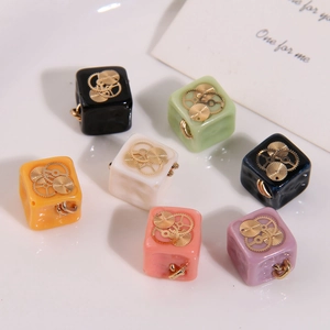 Detailed view of colorful square resin steampunk pendants with golden gear accents