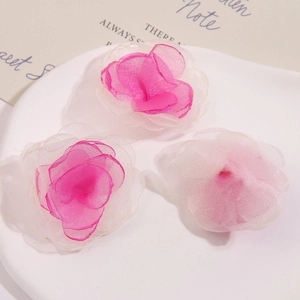 Detail von drei handgefertigten Netzblumen mit rosa Farbverlauf für DIY-Haarschmuck