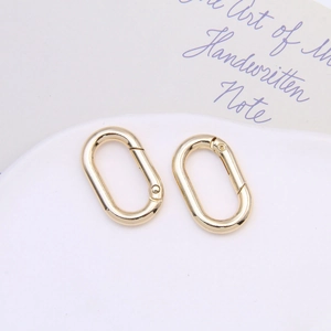 Detail of two oval gold-plated spring rings for DIY jewelry and keychain accessories
