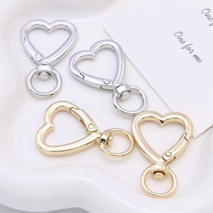 Close-up of gold and silver heart-shaped lobster clasps on a white aesthetic tray