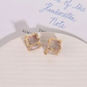 Detail of cubic resin charms with irregular gold-plated edges and metal hanging loops