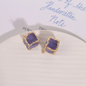 Detailed view of purple cubic gemstone charms with textured gold rim for DIY jewelry