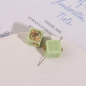 Macro detail of square resin charms with gold gear accents for DIY jewelry making
