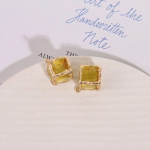 Macro detail of yellow translucent resin square charms with hammered gold metal edges