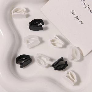 Close-up of black and white plastic decorative shoelace buckles on a white ceramic tray
