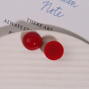 Macro shot of glossy dark red resin round cabochons on a white decorative ceramic plate