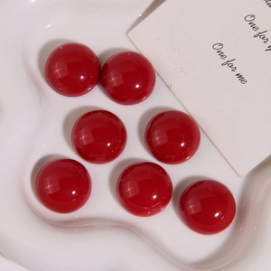 Polished 21mm deep red resin round cabochons for DIY earrings displayed on a ceramic dish