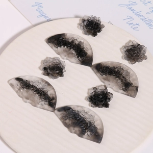 Detailed macro view of resin fan and rose charms with marble smoky grey patterns