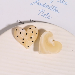 Dettaglio macro di accessori in resina a forma di cuore con marmo e pois neri